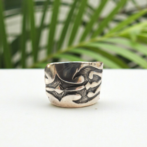 Silver ring on a counter top with a green palm in the background